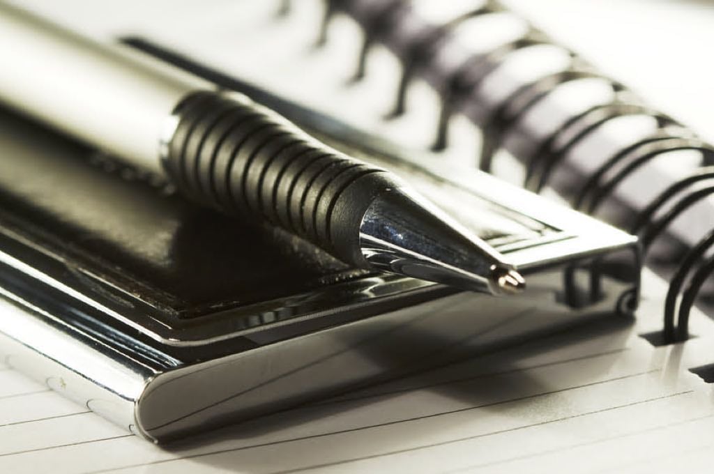 Silver-black pen lying on opened notebook